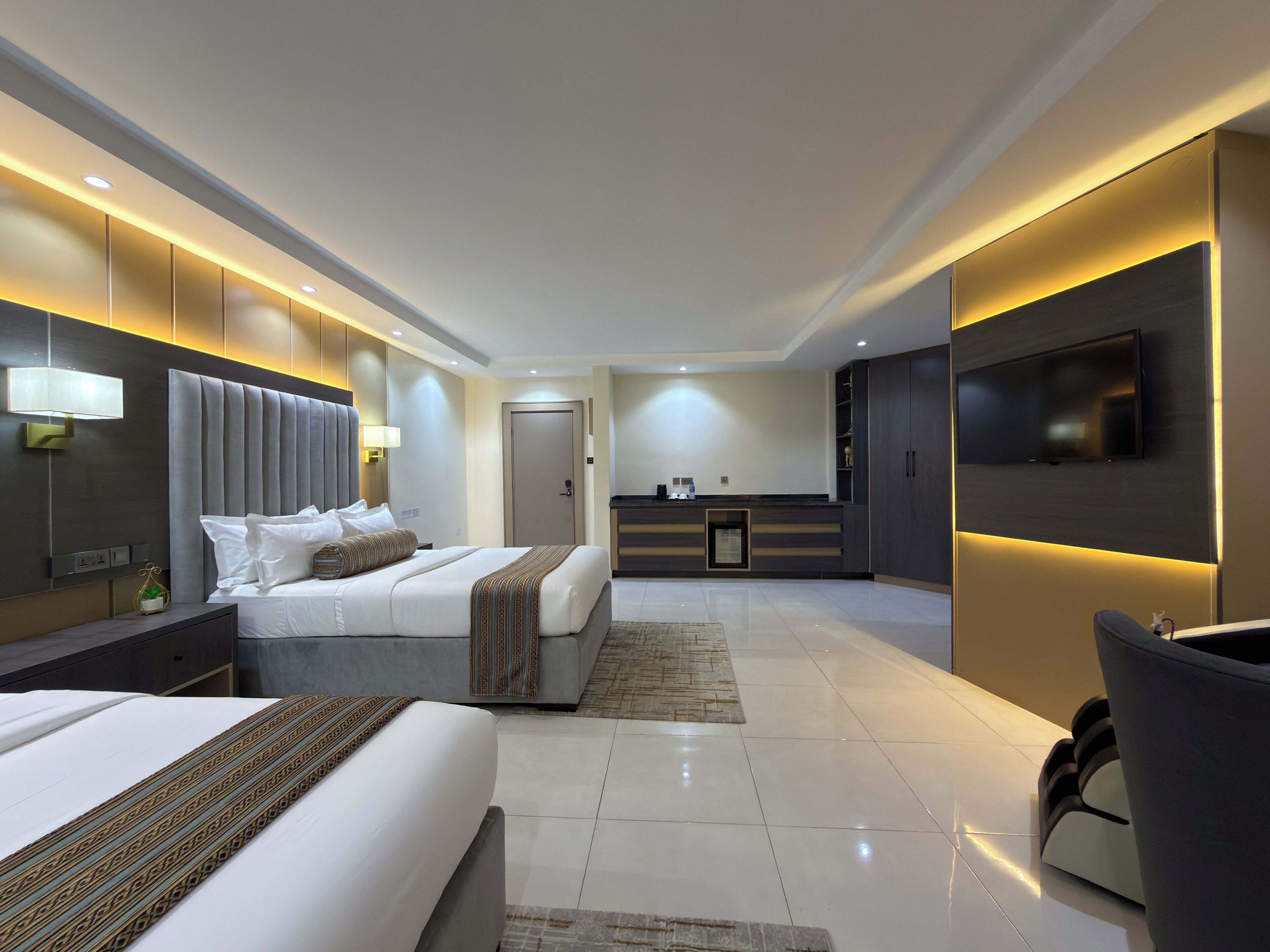 Una moderna camera d'albergo con un letto grande, una scrivania, una TV a schermo piatto e un'area salotto separata.