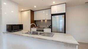 A modern kitchen with white cabinets, stainless steel appliances, and a granite countertop.