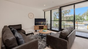 A modern living room with a sofa set, a coffee table, and a TV on a wooden stand.