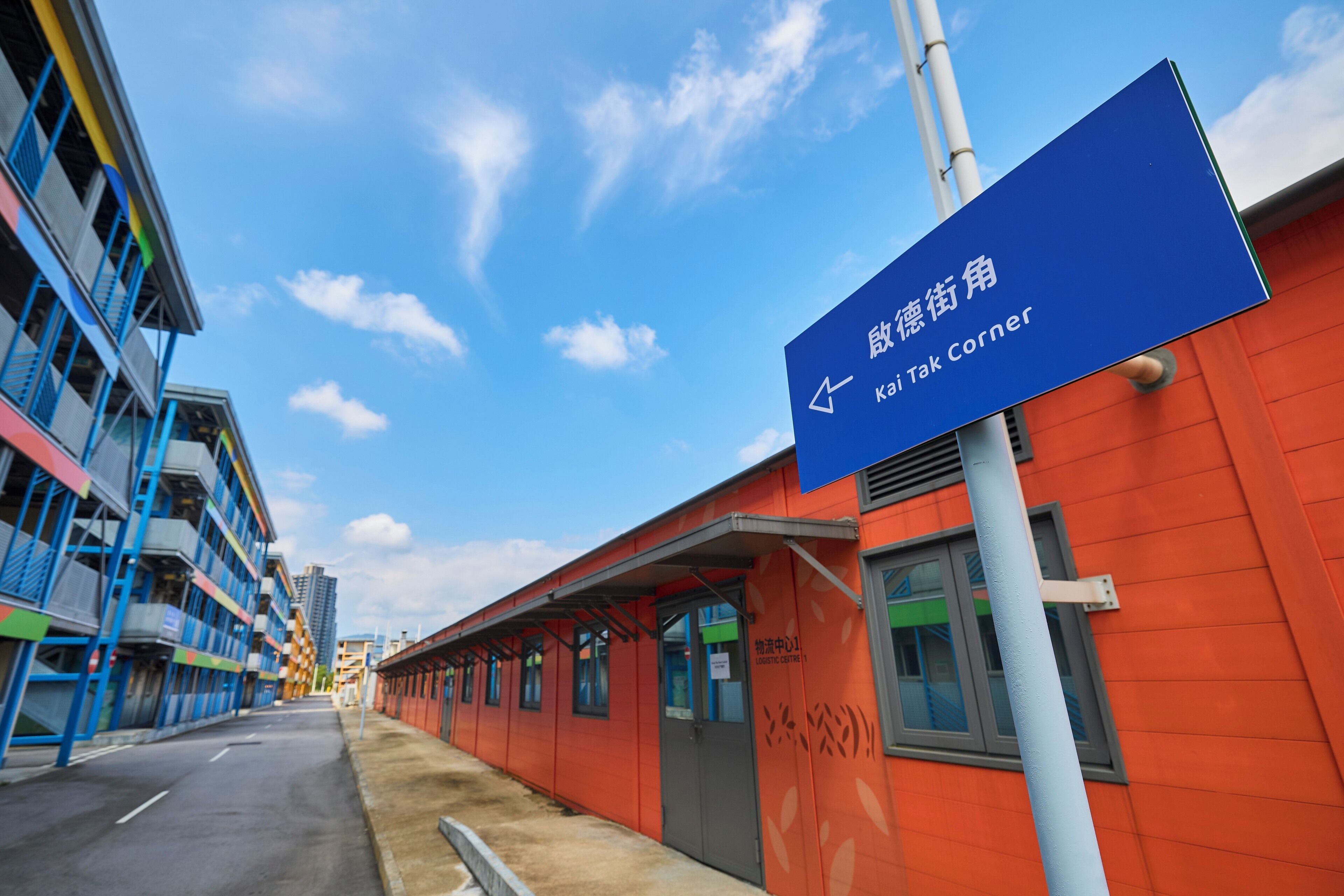 A building with a blue sign indicating the direction to the Kai Tak Corner.
