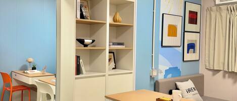 A compact room with a desk, chairs, a bookshelf, and a sofa.