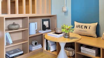 Un interior moderno con estanterías de madera, una mesa redonda con un florero y un cojín con el texto 'iRent Hong Kong'.