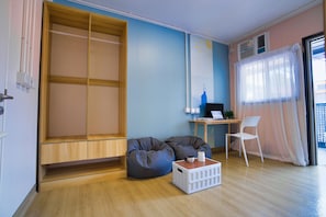 A room with a wooden bench, a desk with a computer, a white chair, and a bean bag. - Runway 1331 - Enlight Youth Hostel (Kowloon)