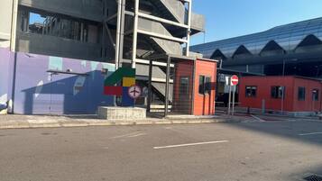 Una parada de autobús con refugio, un paso de peatones y un edificio con fachada de vidrio.
