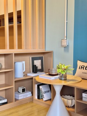 A modern room with wooden shelving, a white table with a vase, and a blue wall. - Runway 1331 - Enlight Youth Hostel (Kowloon)