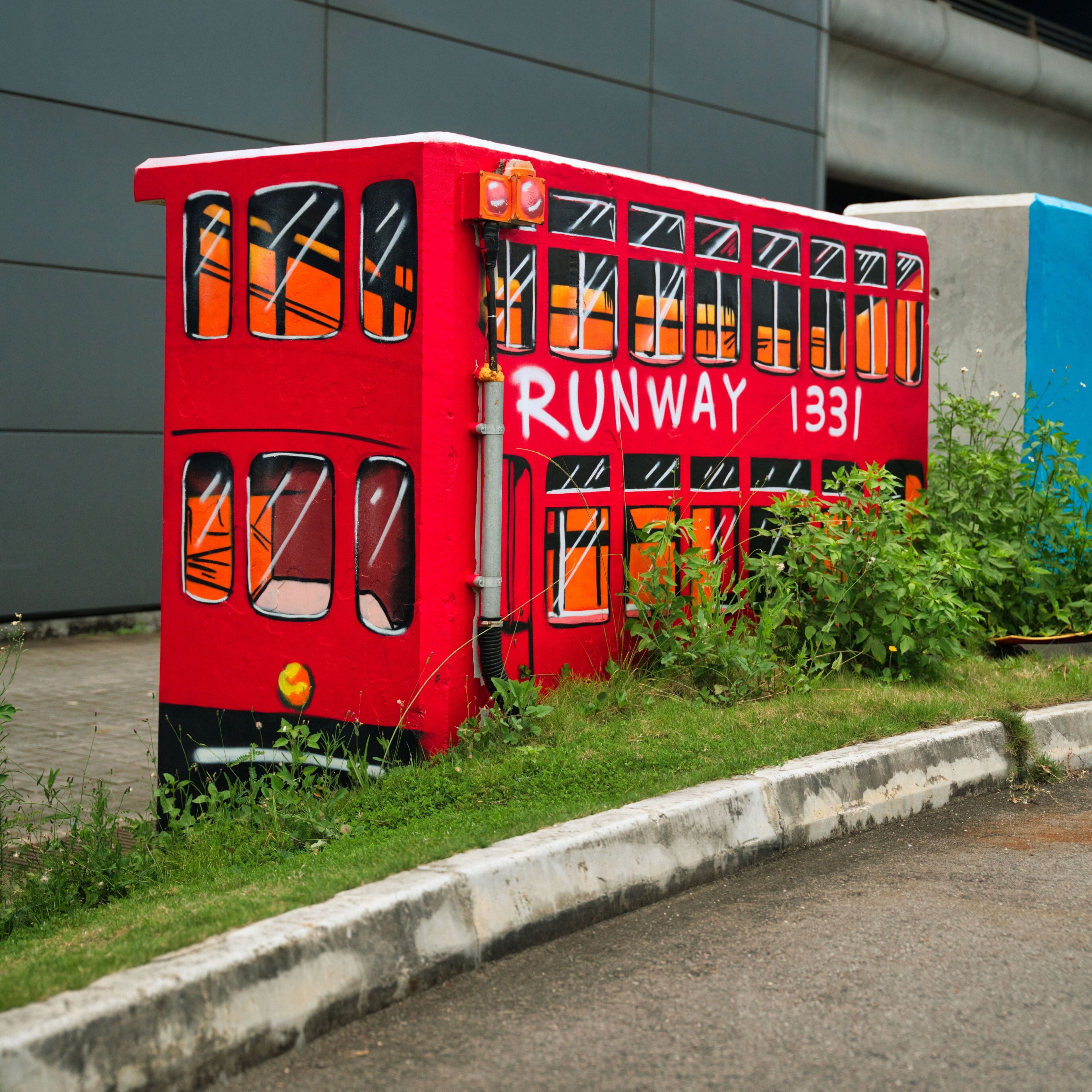 A red double-decker bus with 'RUNWAY 1331' written on its side, parked on a grassy roadside.