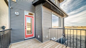 Ein Haus mit einer Holzterrasse, einer roten Tür und Blick auf eine trockene Landschaft.