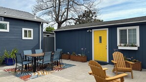 A patio area with a wooden table and chairs, a yellow door, and potted plants. - Welcoming studio in El Cerrito for a cozy getaway (El Cerrito)