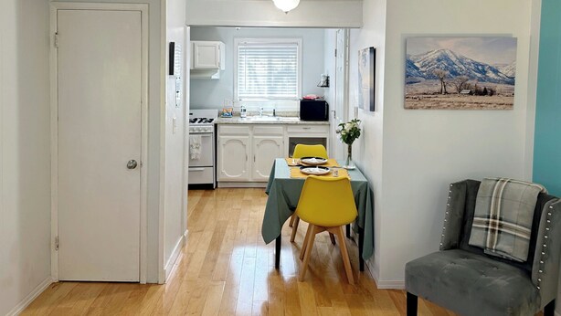 A compact kitchen with white cabinets, a dining table with yellow chairs, and a gray couch. - Welcoming studio in El Cerrito for a cozy getaway (El Cerrito)