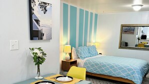 A cozy bedroom with a bed, bedside table, lamp, and a dining area with a table and chairs. - Welcoming studio in El Cerrito for a cozy getaway (El Cerrito)