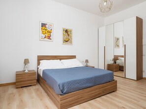 A bedroom with a wooden bed, white walls, and a wardrobe. - Marano Deluxe Apartment – Authentic charm in the heart of Sorrento (Sorrento)