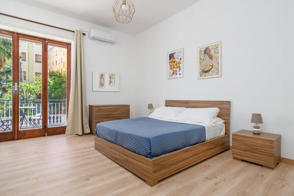 A bedroom with a wooden bed, a nightstand, and a view through a sliding glass door to an outdoor balcony.