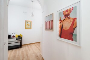 A hallway with a desk, framed artwork, and a light fixture.