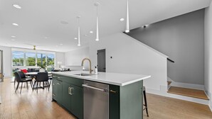 A modern kitchen with a central island, stainless steel appliances, and a dining area with a view.