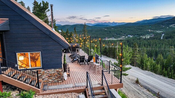 Eine Holzterrasse mit Sitzgelegenheit, Kamin und weiter Bergblick.