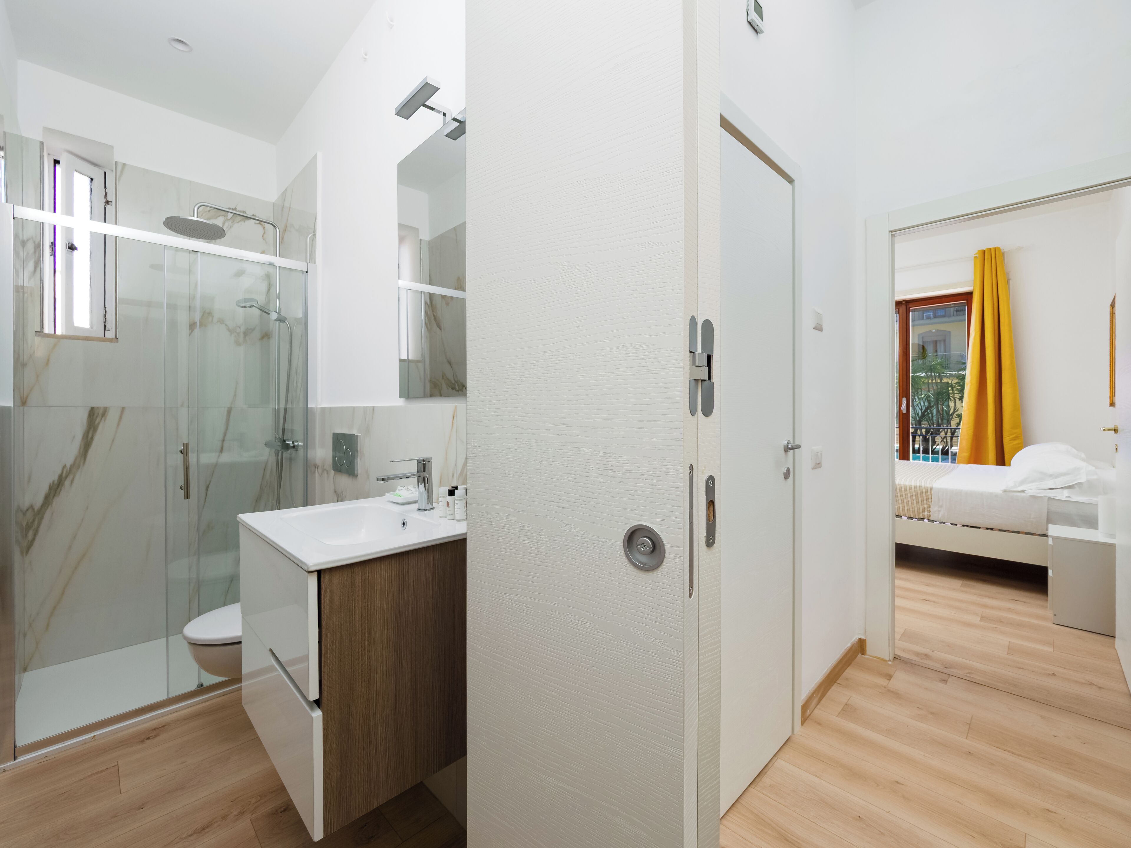A modern bathroom with a glass shower enclosure, a white sink, and a wooden vanity.