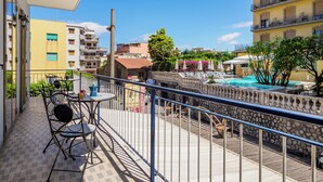 Un balcón con mobiliario exterior, una zona de piscina y un letrero de hotel.