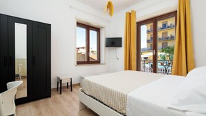 Un dormitorio con cama, escritorio, silla, televisión y ventana con cortinas.