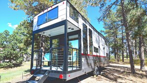 Uma autocaravana moderna com um deck de dois níveis, uma escada para acesso e um interior espaçoso.