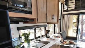 Uma cozinha compacta com fogão, forno, micro-ondas e armários de madeira.