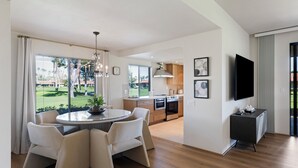 Et moderne køkken med spiseplads, store vinduer og et fladskærms-tv.