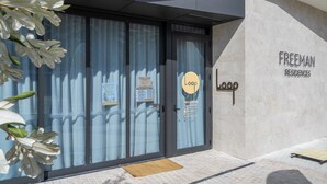 Une entrée moderne avec une porte en verre, une enseigne indiquant « Freeman Residences » et un logo pour « Loop Yoga & Pilates ».