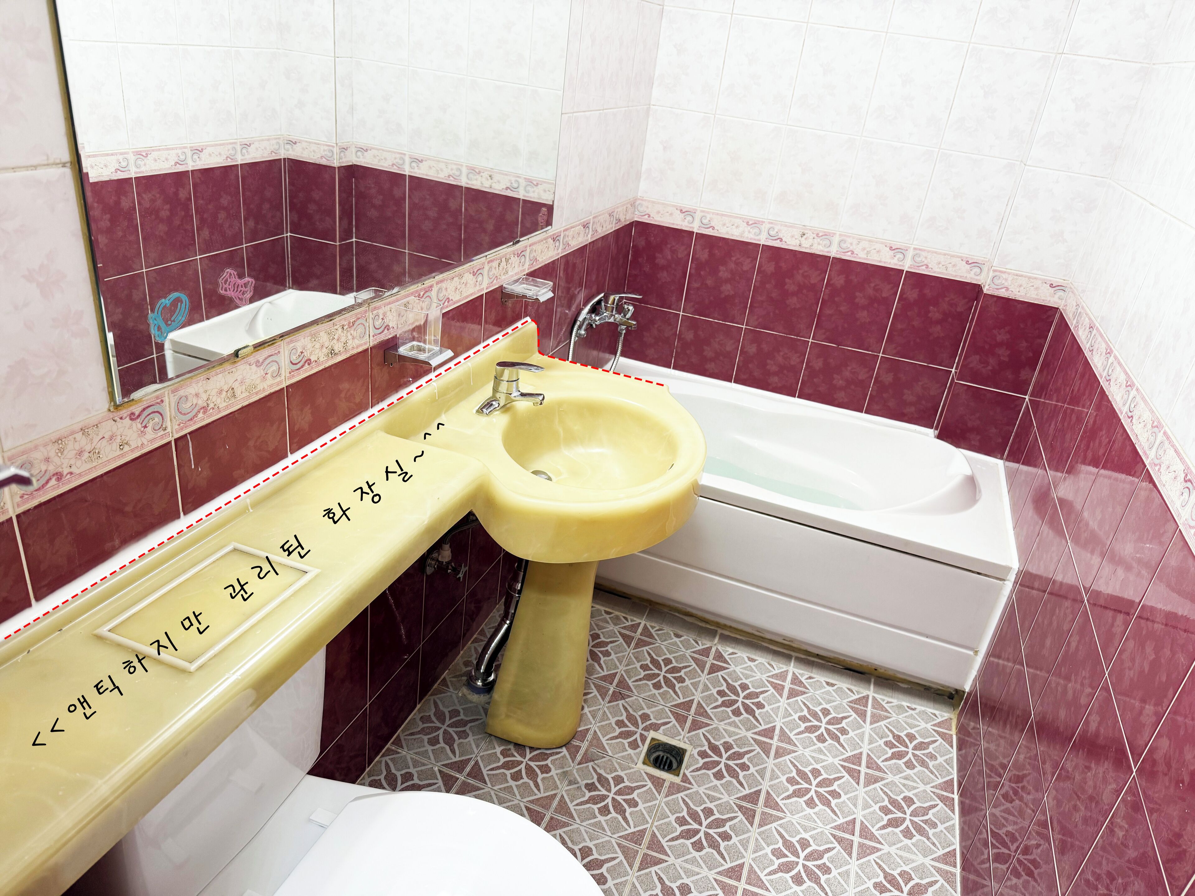 A bathroom with a yellow sink, a white bathtub, and a mirror above the sink.