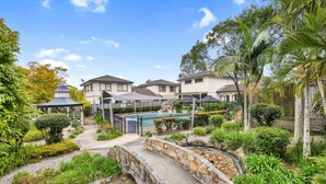 A residential area with multiple houses, a swimming pool, and a stone bridge. - Homely 3-bed Townhouse With Pool & Gym Access (Brisbane)