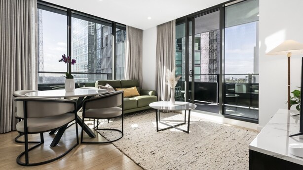 Una sala de estar moderna con una mesa de comedor redonda, un sofá y un ventanal con vista a la ciudad.