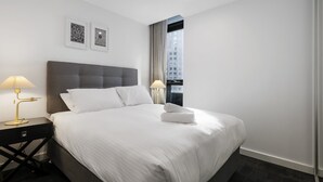 Una habitación de hotel moderna con una cama grande, dos lámparas de noche y obras de arte enmarcadas en la pared.