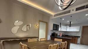 A modern dining area with a wooden table and chairs, a patterned rug, and a contemporary pendant light.