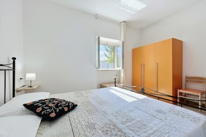 Une chambre à coucher comprenant un lit, une table de chevet, une armoire, une chaise et une fenêtre.