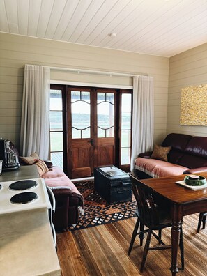 Una habitación acogedora con una mesa de madera, un sofá, una ventana con cortinas y vistas al exterior.