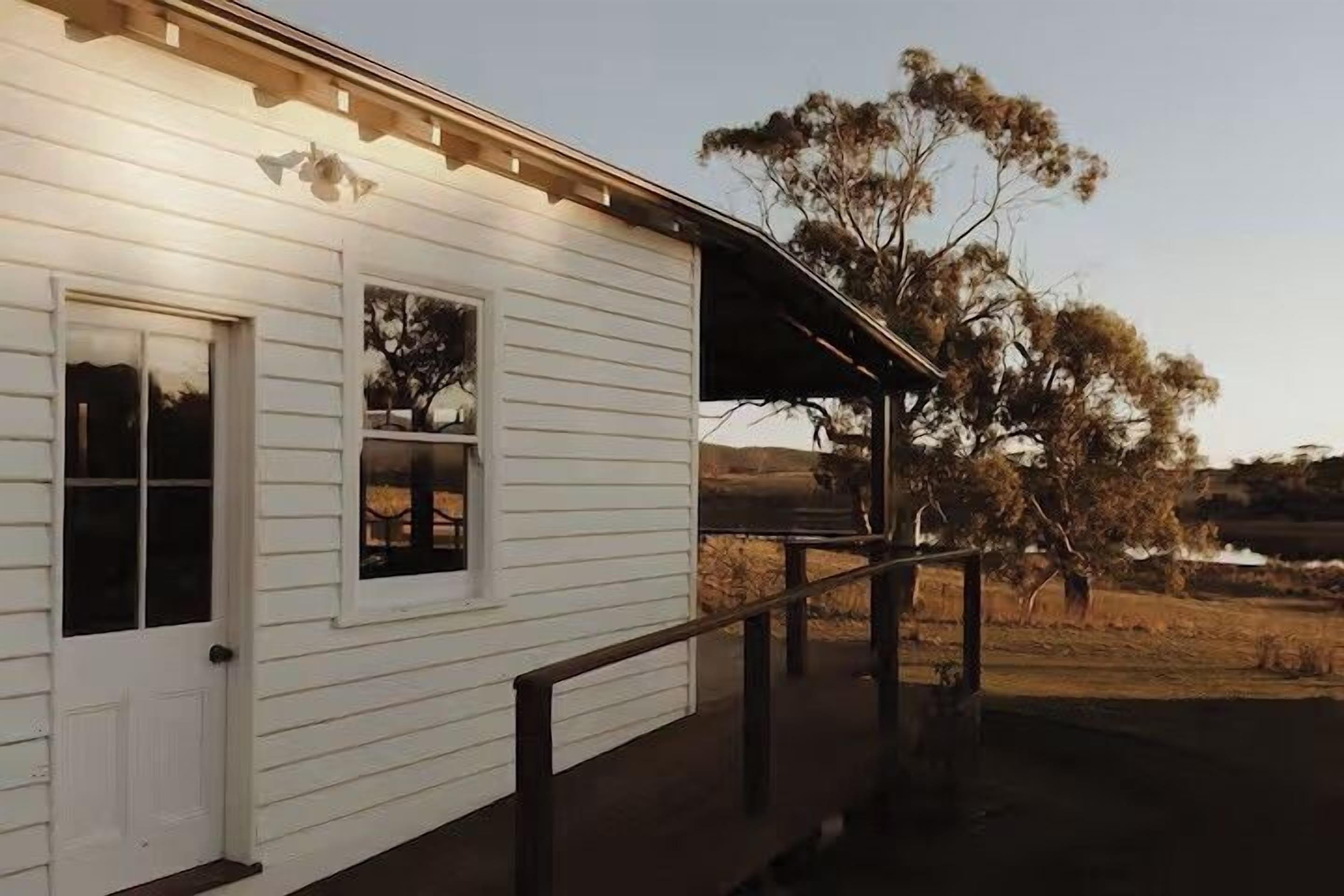 A white building with a porch and a wooden railing.