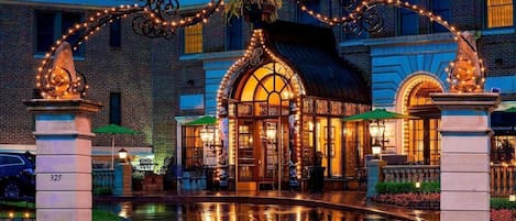 A hotel entrance with a fountain, ornate metalwork, and a warm-lit building facade.