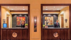 A hotel reception area with two reception desks, each with a framed painting above.