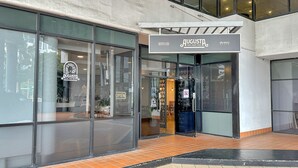 Η εξωτερική όψη ενός εστιατορίου με βραζιλιάνικη θε ματολογία, με μεγάλα τζάμια και μια πινακίδα που υποδεικνύει ότι είναι ανοιχτό.