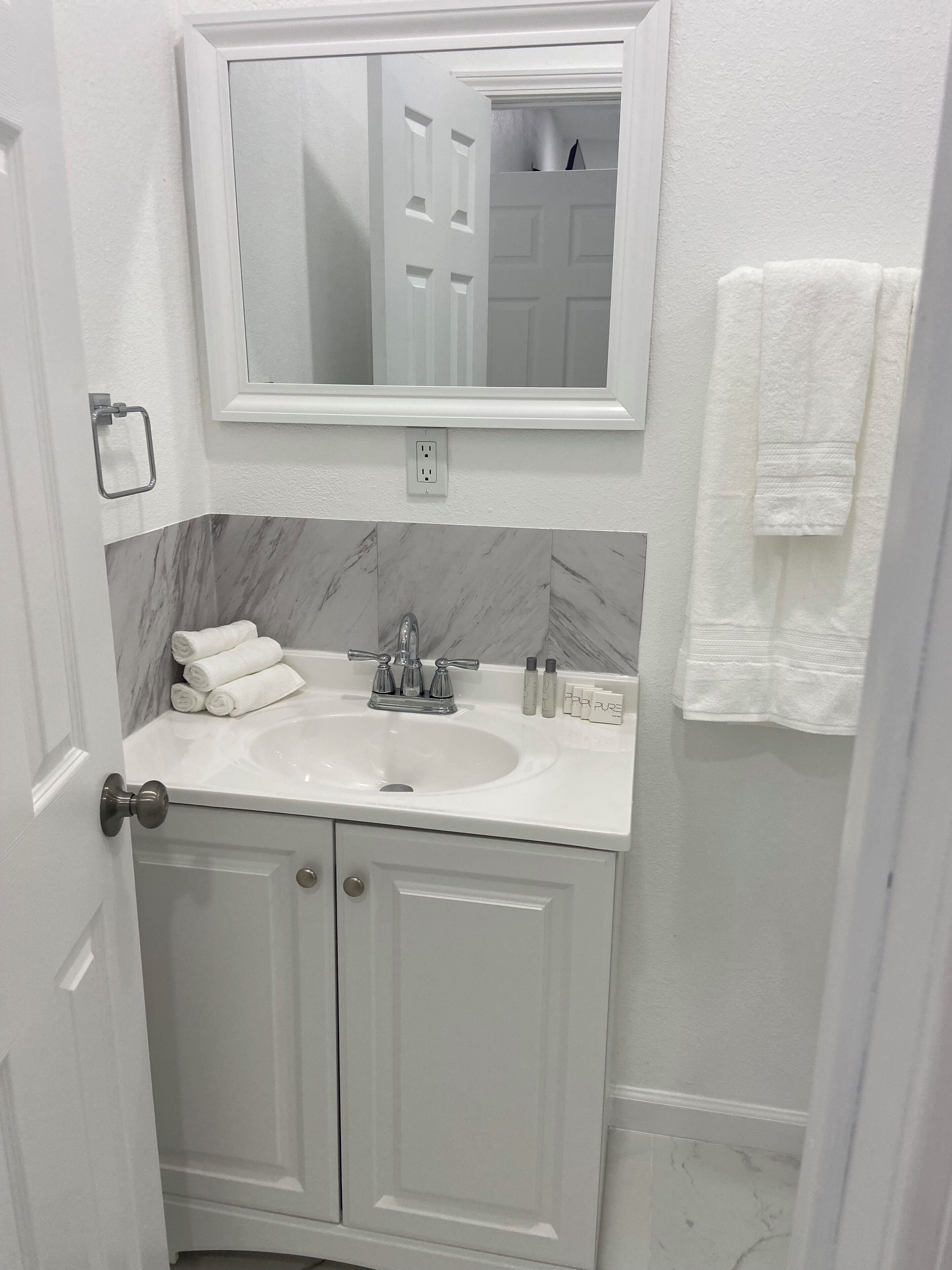 A bathroom with a white sink, a mirror above it, and a towel rack on the wall.
