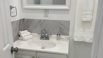 A bathroom with a white sink, a mirror above it, and a towel rack on the wall.