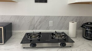 Una cocina con estufa a gas negra, microondas y cafetera.