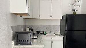 Una cocina moderna con armarios blancos, un refrigerador negro, un horno empotrado y un lavamanos.