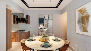 A modern dining area with a round table set for four, surrounded by wooden chairs.