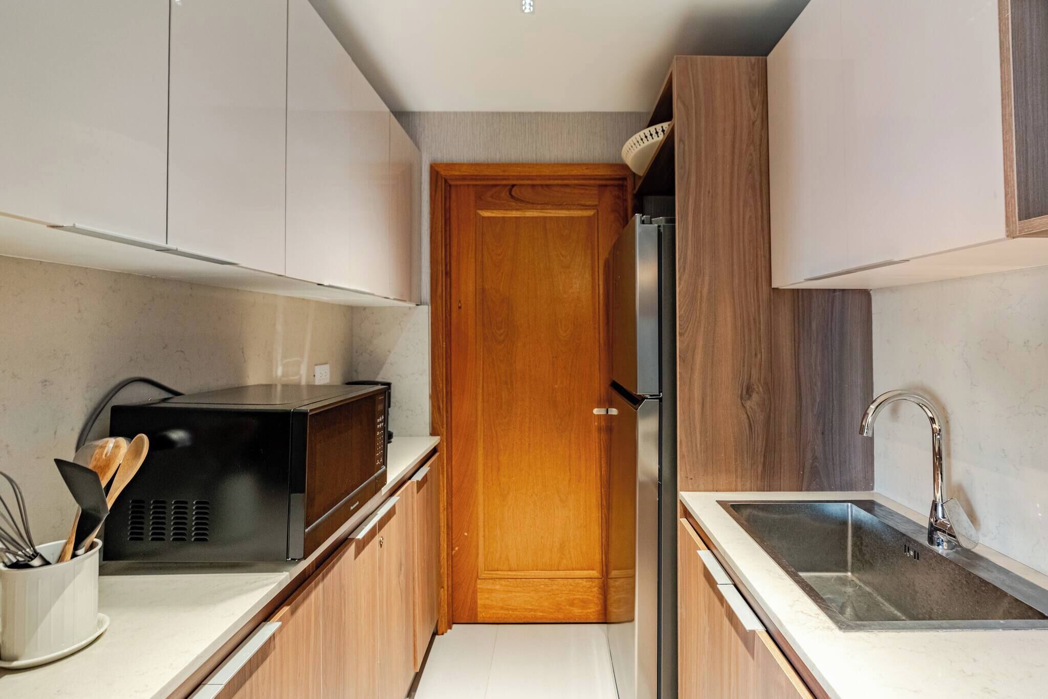 A compact kitchen with a microwave, refrigerator, and sink.