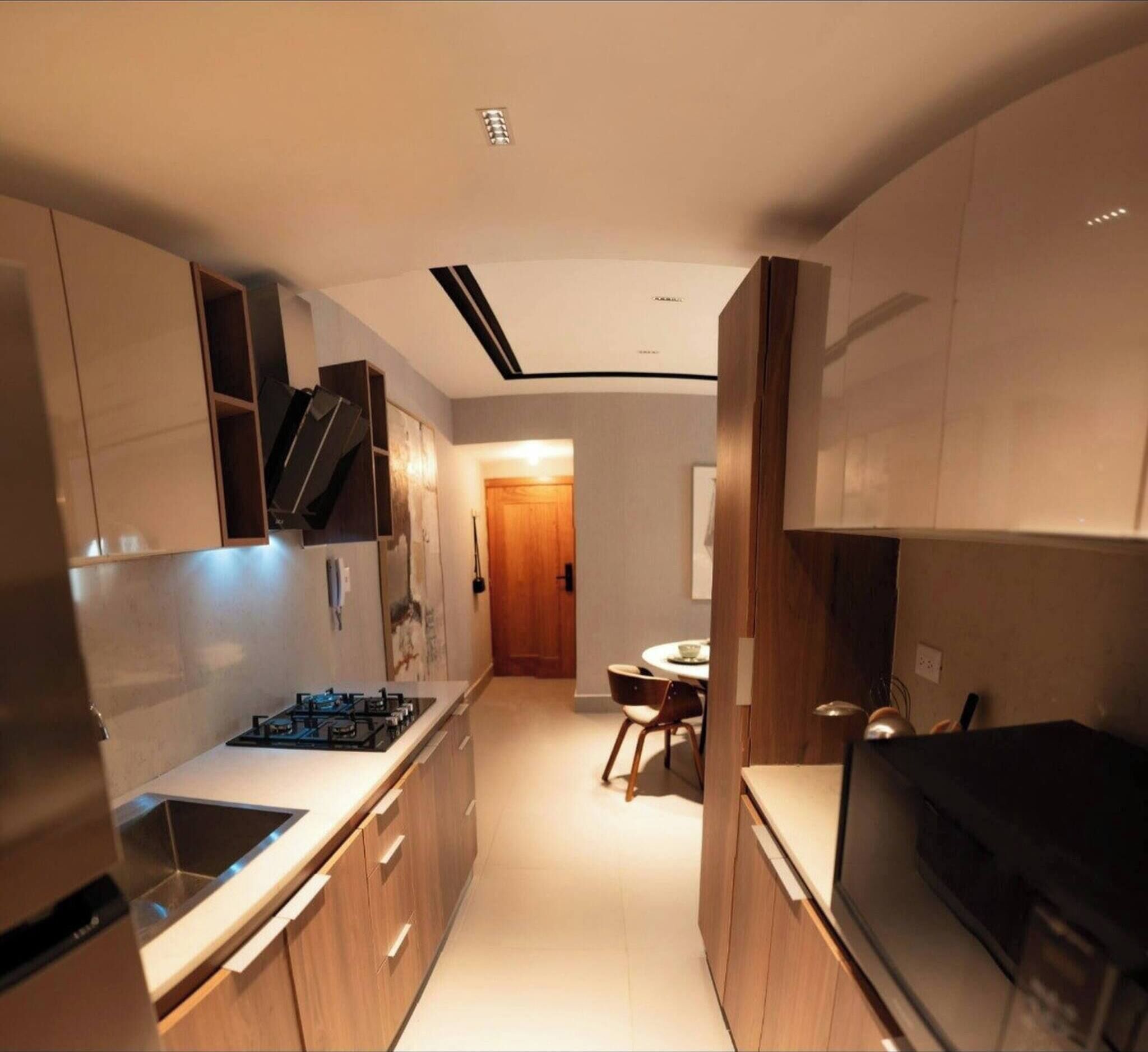 A modern kitchen with wooden cabinets, a built-in stove, and a dining area with a round table and chairs.