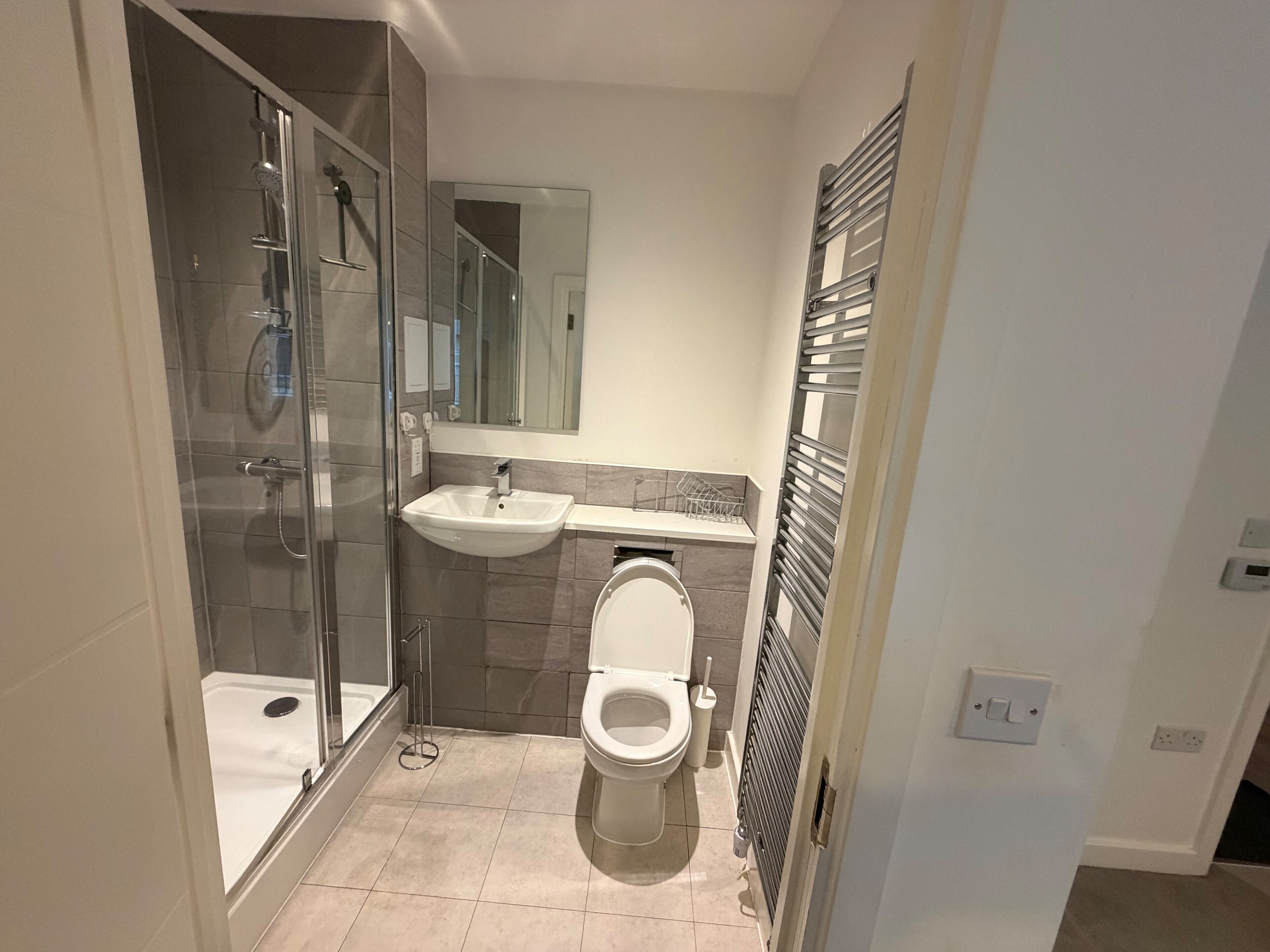 A modern bathroom with a glass shower enclosure, a sink, and a toilet.
