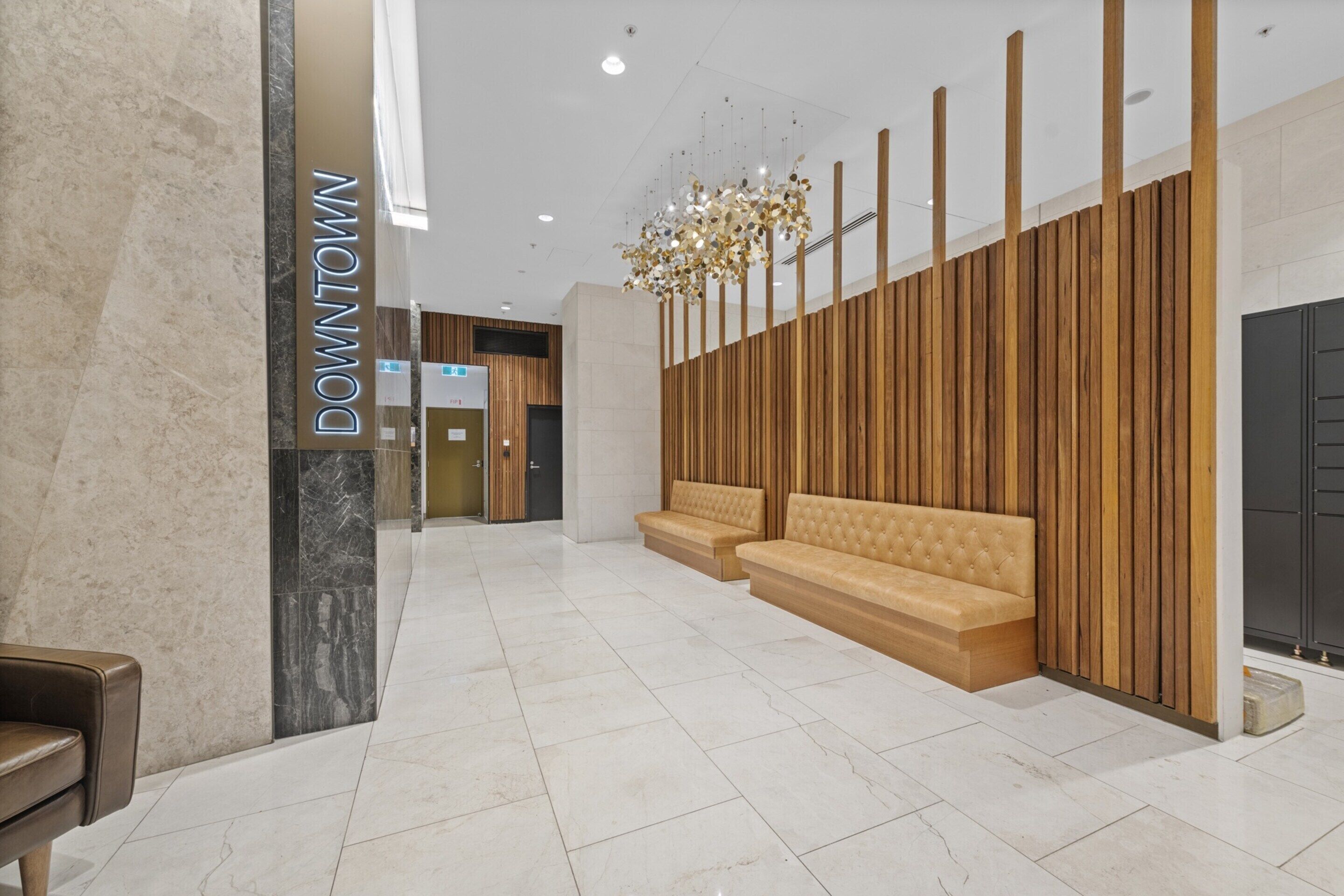 Um lobby moderno com piso de mármore, painéis de madeira e uma placa com a inscrição "DOWNTOWN".