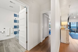 A hotel room with a wooden floor, a glass shower, and a view of the sea.