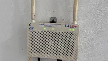A white SLT Fibre router with two antennas, a power cable, and a label with a Wi-Fi password.