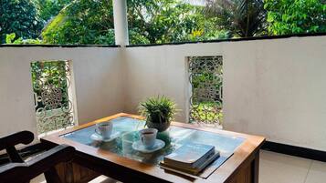 Een glazen tafel met twee kopjes en een boek, voor een witte muur met decoratieve metalen panelen.
