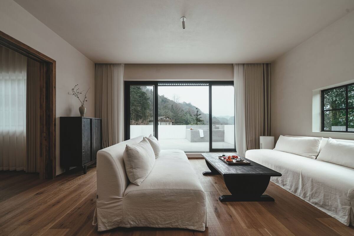 A modern living room with a sofa, a coffee table, and a view of a balcony.